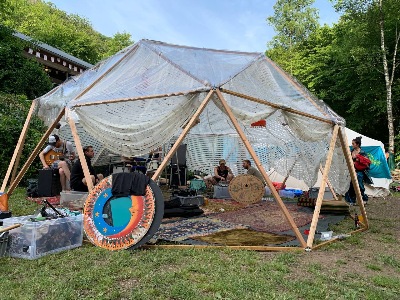 Die Geokuppel als Bühne auf einem Festival: eine Band spielt unter der transparenten Kuppel am Waldrand